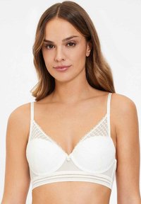 Soutien-gorge blanc avec un bord en dentelle et des bonnets rembourrés doux. La base est lisse avec des accents en mesh décoratifs. Bretelles fines réglables.