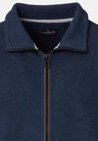 Giacca blu navy con cerniera lampo, tessuto a coste, collo alto, fodera interna a contrasto e cerniera centrale con cursore nero.