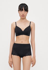 Black bra and high-waisted brief set. Bra features a v-neck design and scalloped lace trim. Brief has lace sides and smooth fabric.