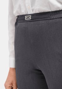 Grijze op maat gemaakte broek met een gladde textuur, voorzien van een slanke zilveren gesp riemaccent. Gestyled met een witte button-up shirt.
