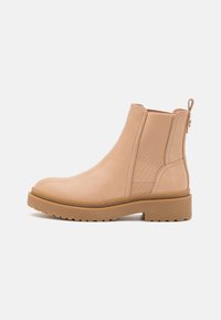 Beiga läderankelboots med elastiska sidopaneler, rund tå och en texturerad gummisula; har en dragflik baktill.