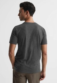Tricou gri cu mânecă scurtă, fabricat dintr-un material moale, având un guler de tip crew neck și o siluetă ajustată, văzut din spate.