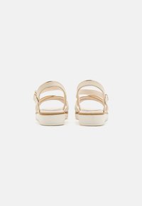 Tan sandals with a smooth finish, featuring three adjustable straps and a cushioned sole for comfort. White platform base.