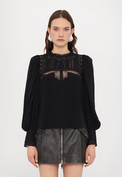 Black blouse with long puffed sleeves, lace detailing on the chest and neckline, and pleated body. Paired with a dark leather mini skirt.