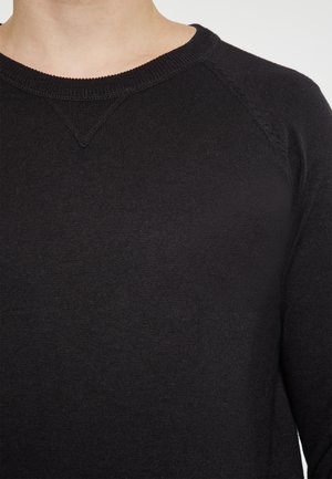 Sort strikket sweater med rund hals, raglanærmer og ribbede manchetter, der har en glat tekstur og et enkelt design.