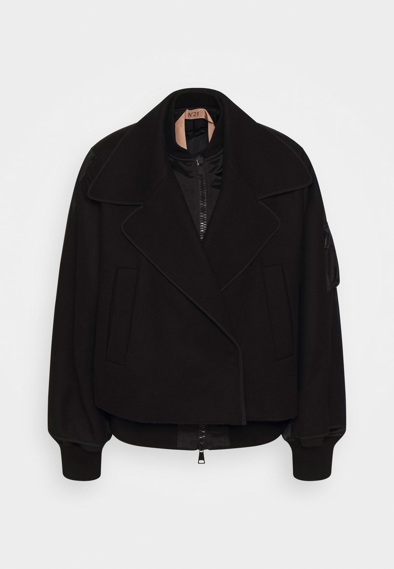 Veste courte noire avec larges revers, fermeture éclair devant, poignets côtelés, poches latérales et une poche zippée sur la manche gauche, suspendue sur fond blanc.