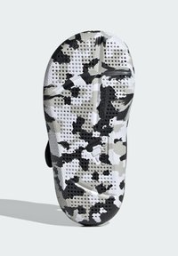 Sole con motivo camouflage bianco e nero, dotata di grip testurizzato e fori di drenaggio, con logo impresso lungo il centro.