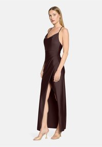 Robe de soirée en satin brun foncé avec fines bretelles, encolure drapée et fente latérale haute ; texture lisse avec une silhouette ajustée.