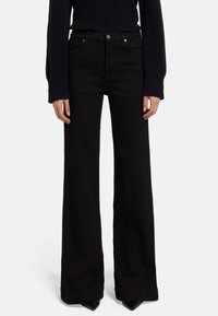 Jeans anchos negros de mezclilla, con una cintura alta, bolsillos frontales y cierre de botón. Textura suave con detalles de costura mínimos.