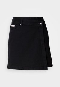 Mini-jupe noire style portefeuille avec passants de ceinture, fermeture devant par boutons et petite étiquette avec le logo Calvin Klein près de la poche.