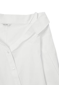 Chemise en coton blanc avec un col plié et une fermeture à boutons. Présente des plis latéraux et une étiquette indiquant "CALLIOPE" en taille petite.