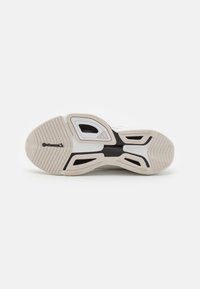 Suela de zapatilla blanca con un caucho beige texturizado, distintivos acentos negros y un logo de Continental. Cuenta con surcos para tracción y flexibilidad.