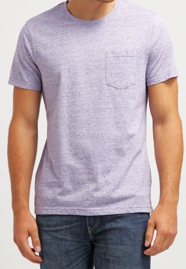 Mężczyzna w jasnofioletowej, melanżowej koszulce z krótkim rękawem i kieszonką na piersi oraz ciemnoniebieskich dżinsach.