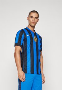 Nike nogometna majica s vertikalnim crnim i plavim prugama, teksturirana tkanina, dizajn s V-izrezom i grbom smještenim na sredini prsnog dijela.