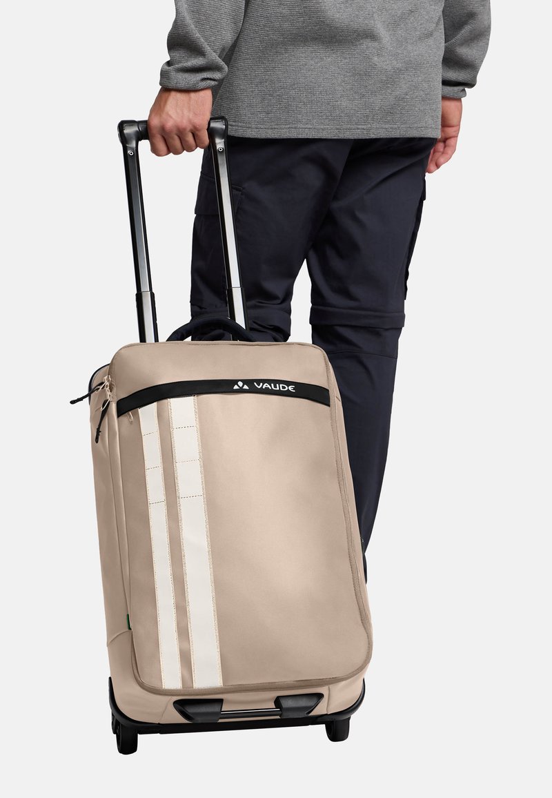 Valigia a rotelle beige con un design strutturato, dotata di una cerniera nera, strisce verticali crema e un manico estraibile.