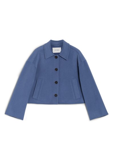 Giacca blu chiaro tagliata, realizzata in tessuto morbido. Presenta un colletto a punte, chiusura con bottoni, due tasche frontali e maniche ampie.