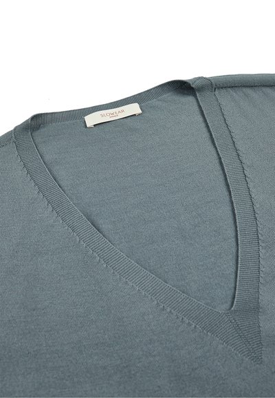 V-ausschnitt Pullover aus weichem, blau-grauem Stoff. Sauberer Stich an den Kanten, mit einem Etikett am Halsausschnitt. Schlichtes, minimalistisches Design.