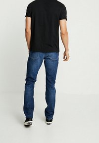 Jeans de mezclilla azul oscuro con un diseño de pierna recta, que presentan detalles de costura sutiles y un clásico diseño de cinco bolsillos.