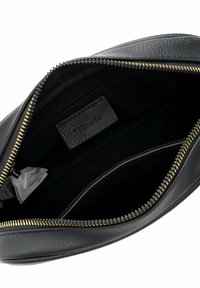 Black leather clutch bag interior with gold zipper, features a textured label. Lined with black fabric and includes a side pocket.