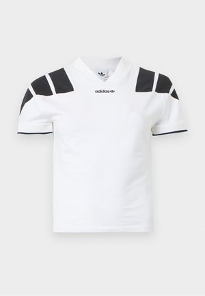 Chemise blanche à manches courtes avec des accents noirs sur les épaules et le col. Présente un col en V et le logo Adidas sur le devant. Matière en coton.