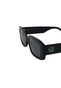 Čierne slnečné okuliare so lesklým povrchom, štvorcové šošovky a tmavošedý nádych. Obsahujú zelené logo na ramenách a široké, robustné ramená.
