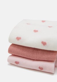 Tres pares de calcetines apilados. El calcetín superior es blanco con estampados de corazones rosas, el del medio es de color rosa sólido y el de abajo es de un rosa claro con patrones de corazones.