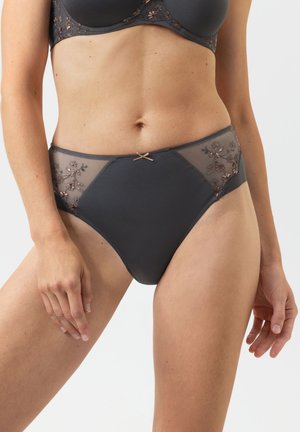 Frau trägt dunkelgrauen BH und passende hochgeschnittene Slips mit bestickten floralen Spitzenpaneelen und kleinem Schleifendetail vorne.