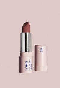 Korres True Velvety Lipstick med en krämig, matt mauve-färg i en cylindrisk tub. Kapsylen är ljusrosa med blå text.
