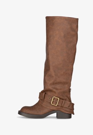 Bruine kniehoge laars met lage blokhak en decoratieve riem met metalen gesp rond de enkel.
