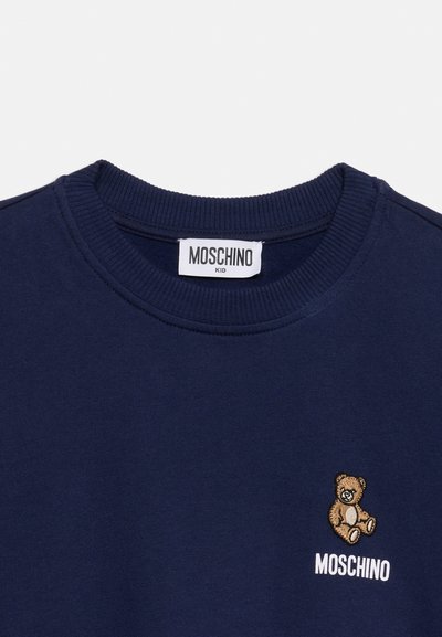 Μπλούζα Moschino Kid σε ναυτικό μπλε με ριμπ λαιμόκοψη, κεντητό αρκουδάκι και λευκό λογότυπο Moschino στο στήθος.