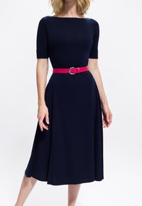 Marineblaues knielanges Kleid mit tailliertem Oberteil, kurzen Ärmeln und ausgestelltem Rock, akzentuiert durch einen hellrosa Gürtel mit silberner Schnalle.