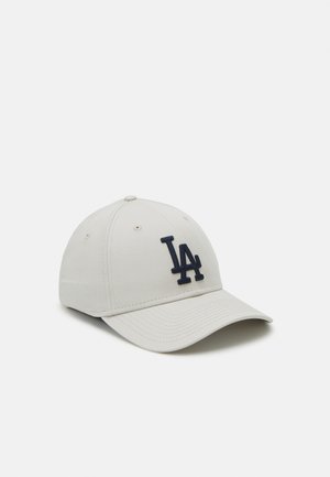 Beige Baseballkappe mit gebogenem Schirm und gesticktem dunkelblauen "LA"-Logo auf der Vorderseite. Hergestellt aus Stoff mit sichtbaren Nähdetails.