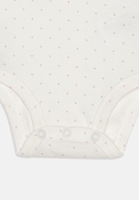 White cotton bodysuit featuring small pink polka dots, with a lap neck and snap closures at the bottom for easy dressing.