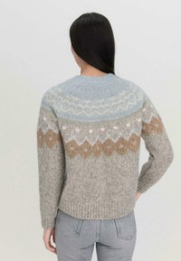 Neulepaita pyöreällä kaula-aukolla, jossa on vaaleansininen yoke, beige- ja harmaasävyinen kuviointi, pehmeä viimeistely ja riipputakki.