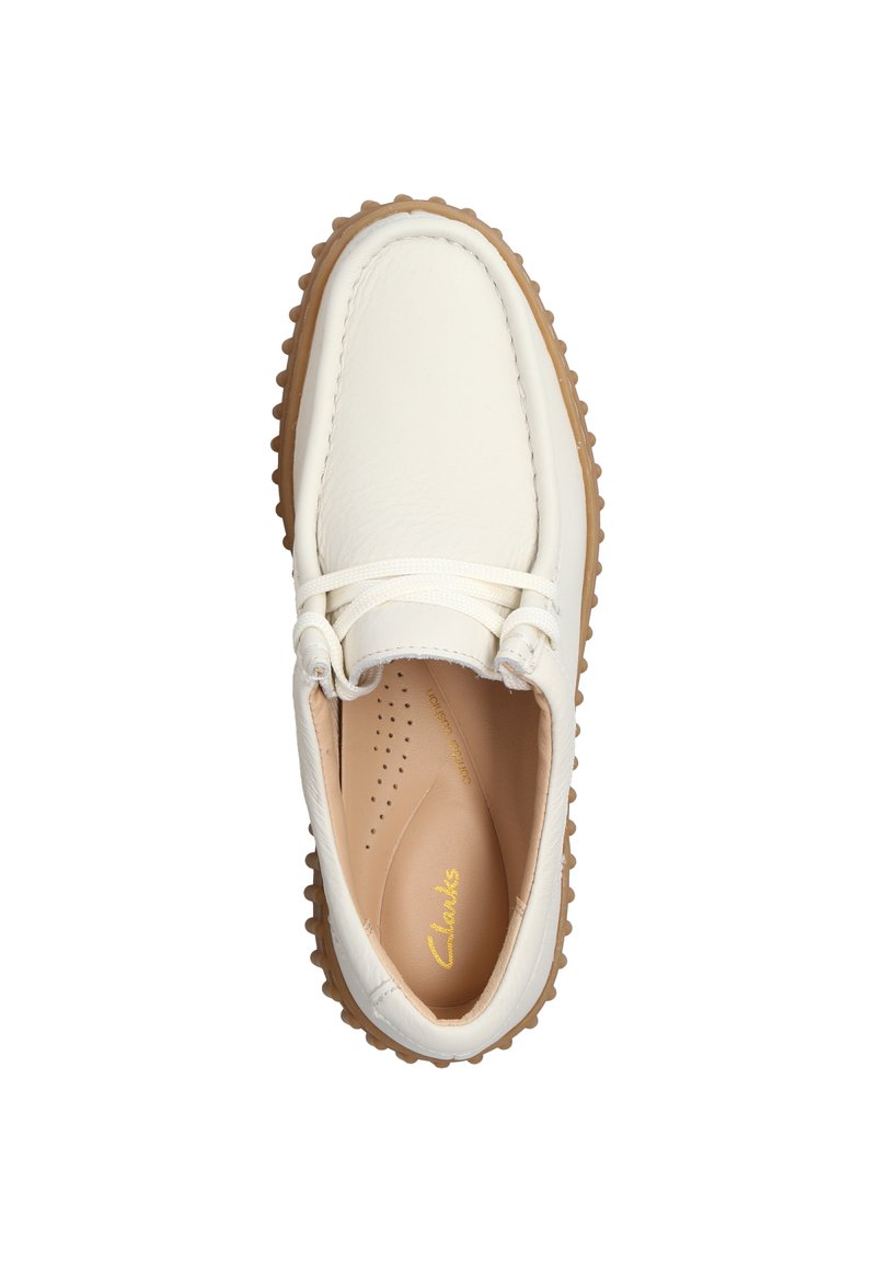 Scarpa in pelle bianca con punta arrotondata, suola in gomma beige e lacci tonali. L'interno presenta perforazioni e un marchio dorato.