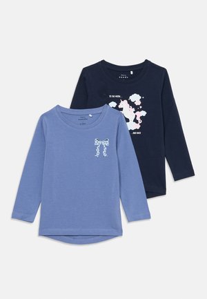Zwei Langarm-Kinderhemden, eines blau mit einem gepunkteten Schleifenprint, das andere marineblau mit einem Einhorn- und Wolkenmuster.