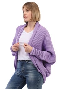 Helllila gerippter Cardigan mit Schalkragen, langen Ärmeln und strukturiertem Stoff, getragen über einem weißen T-Shirt mit blauen Jeans.