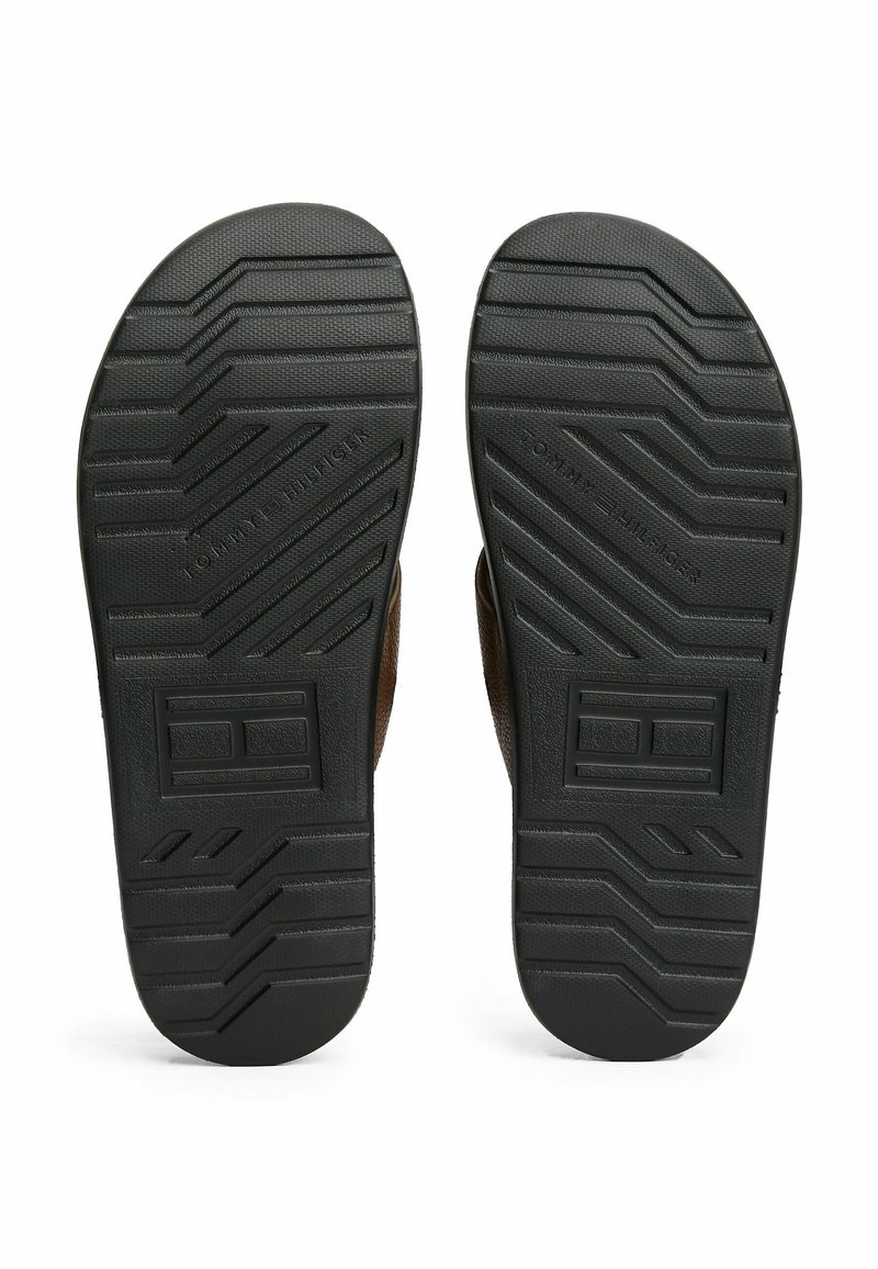 Brązowe klapki typu flip-flop z teksturowanymi czarnymi gumowymi podeszwami, z wzorem w zygzak i wytłoczonym logo. Paski wykonane są z miękkiego materiału.