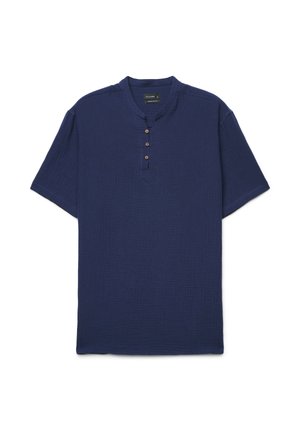 Chemise bleu marine à manches courtes avec trois boutons marron sur un col rond et tissu texturé.