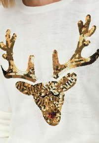 Witte trui met een rendierkopontwerp van goud- en zilverkleurige pailletten, met een rode paillettenneus en bruine takken.