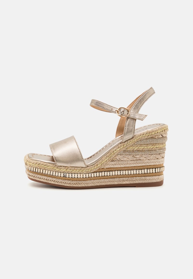 Sandale à talon compensé en or métallique avec une large sangle et une bride à la cheville. Présente des détails en jute tissé naturel et une semelle intercalaire texturée.