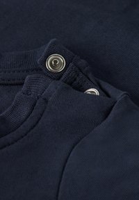 Marineblauw katoenen kledingstuk met een ronde hals en drukknoopsluiting, voorzien van een geribbelde structuur en gladde stofdetail.