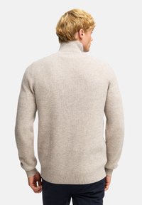 Hellgrauer, gerippter Strickpullover mit hohem Kragen, langen Ärmeln und strukturierter Optik. Verfügt über enganliegende Bündchen und Saum.