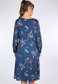 Blumenkleid aus dunkelblauem Stoff. Lange Ärmel mit gerafften Bündchen, Blumendesign in Schattierungen von Rot, Lila und Gelb. Abnäher an der Taille.