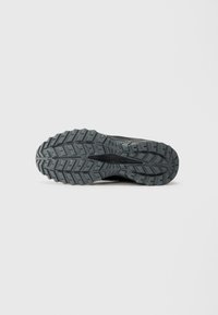 Semelle de sneaker noire avec un motif de crampons robuste pour une meilleure adhérence, fabriquée en caoutchouc durable avec des rainures texturées et des détails uniques.