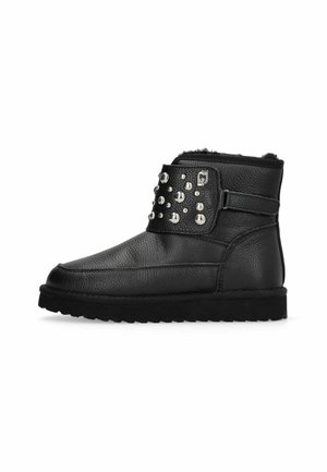 Black ankle boot with textured leather, studded strap across front, and fur lining visible at top edge.
