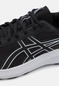 Black athletic shoe featuring a textured mesh upper, white accent lines, and a rubber sole with ridges for traction.