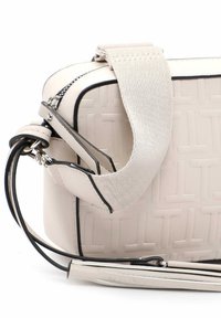 Borsa a mano in pelle beige con motivo embossato, dotata di tracolla rimovibile e dettagli in metallo nero. Texture liscia e design strutturato.