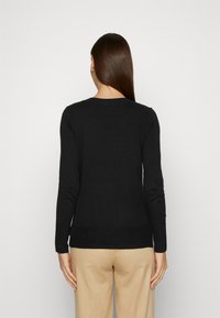 Svart långärmad tröja med rund halsringning, tillverkad av ett mjukt tyg, med en slät yta och en figursydd siluett.