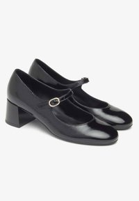 Schwarze Leder-Mary-Jane-Schuhe mit runder Spitze, mittelhohem Blockabsatz und verstellbarem Riemen, der mit einer dekorativen Schnalle verziert ist.